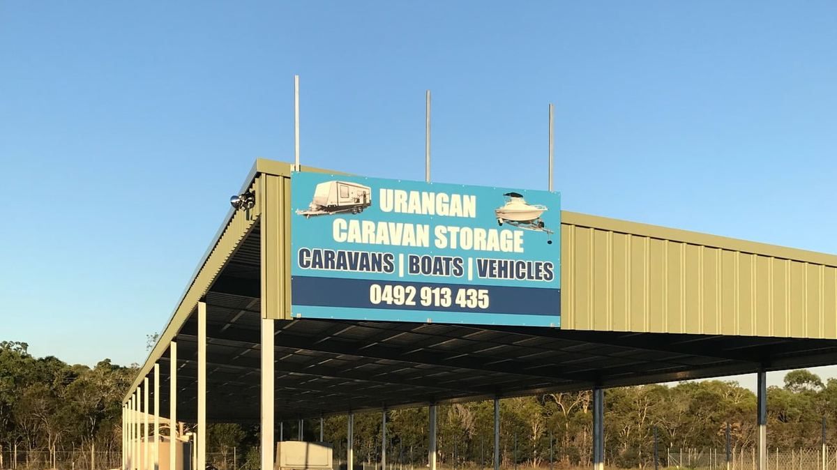 The long covered shelter at Urangan Caravan Storage, with the Urangan Caravan Storage sign mounted on the green Colorbond roof above the steel posts.
